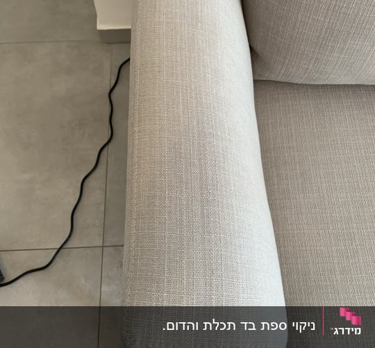 ספה בהירה עם כבל חשמלי על הרצפה